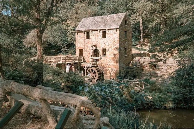 Charming old stone mill with water wheel surrounded by trees and nature. Perfect for rustic and outdoor decor themes.