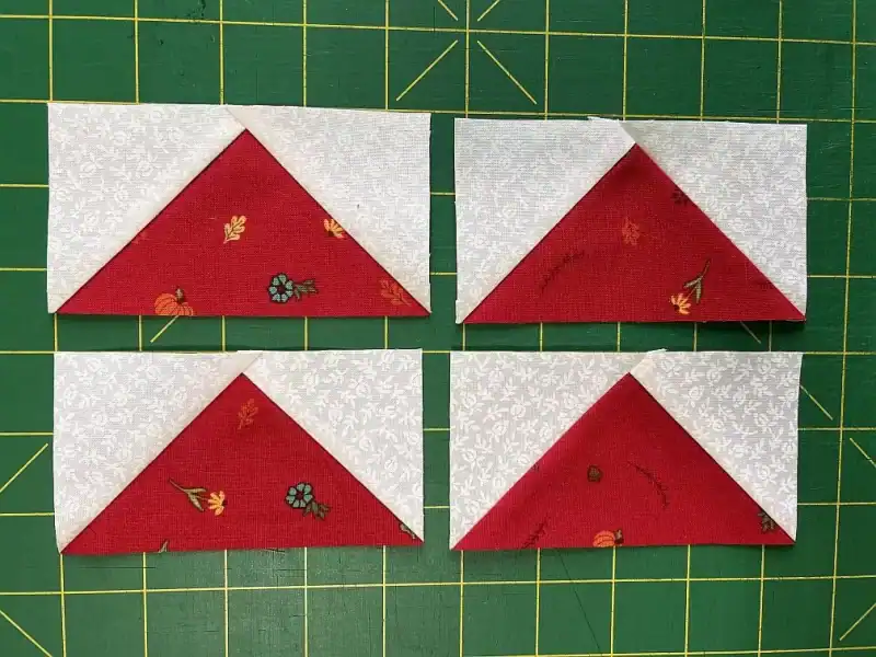 Colorful quilt corner triangles on holiday-themed fabric. Perfect for Christmas quilting projects.