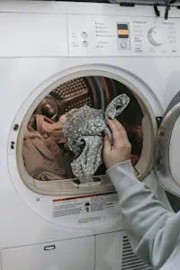 Crop unrecognizable female loading dirty clothes in modern white washing machine while doing housework routine in light room at home. Photo by Sarah Chai