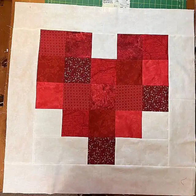 Colorful red fabric quilt square with festive patterns.