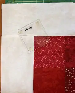 Clear quilting ruler on red and white fabric squares, perfect for quilt patchwork and sewing projects.
