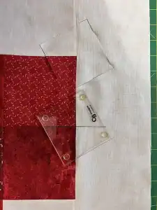 Alt: Transparent quilting template on fabric with red and white patterns, for precise cutting.