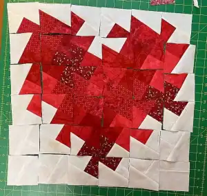 Colorful handmade Christmas quilt block with red and white fabric pieces.