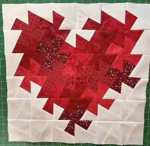 Colorful Christmas quilt block with red and white fabric, perfect for holiday decorations and quilting projects.