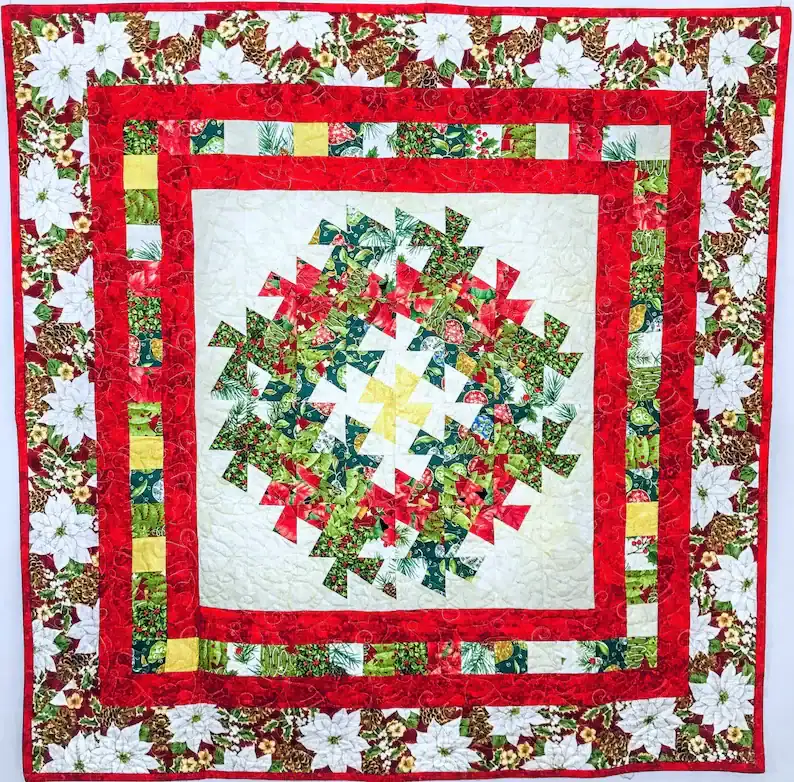 Colorful Christmas quilt with intricate pinwheel patterns in green, red, yellow, and white. Surrounded by red and white borders featuring poinsettia flowers, creating a festive holiday design.